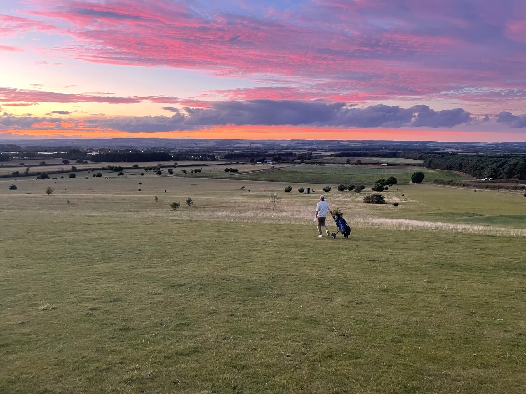 Golfer approaching the green at sunset